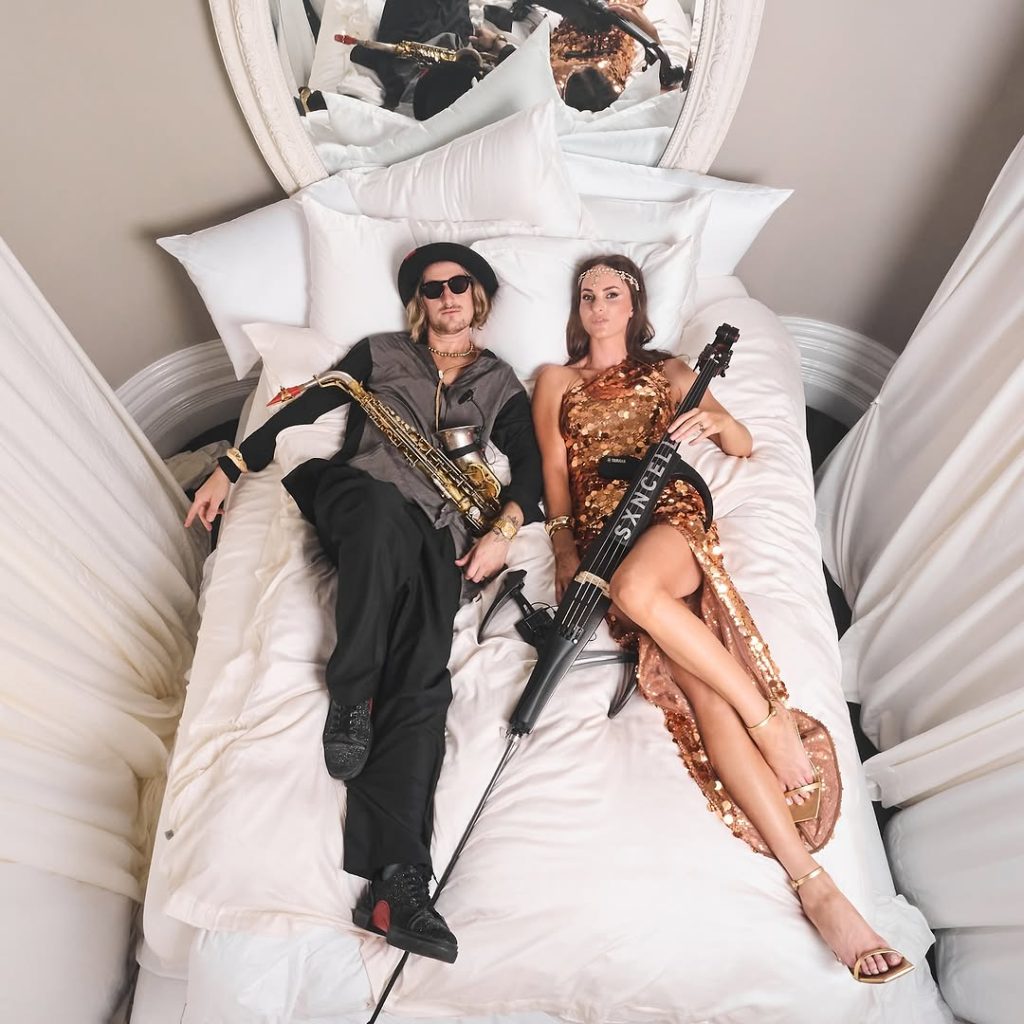Stylised promotional photo of SXNCELLO duo in performance attire with saxophone and a cello